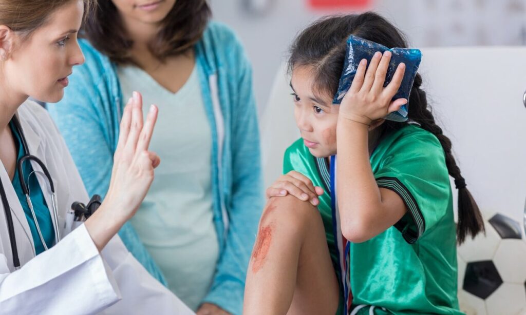 Doctor checking on a young female soccer player after a head injury