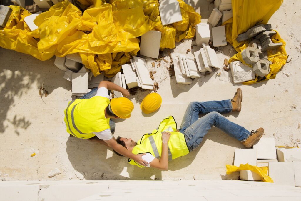 Construction worker tending to an injured coworker after a fall on site