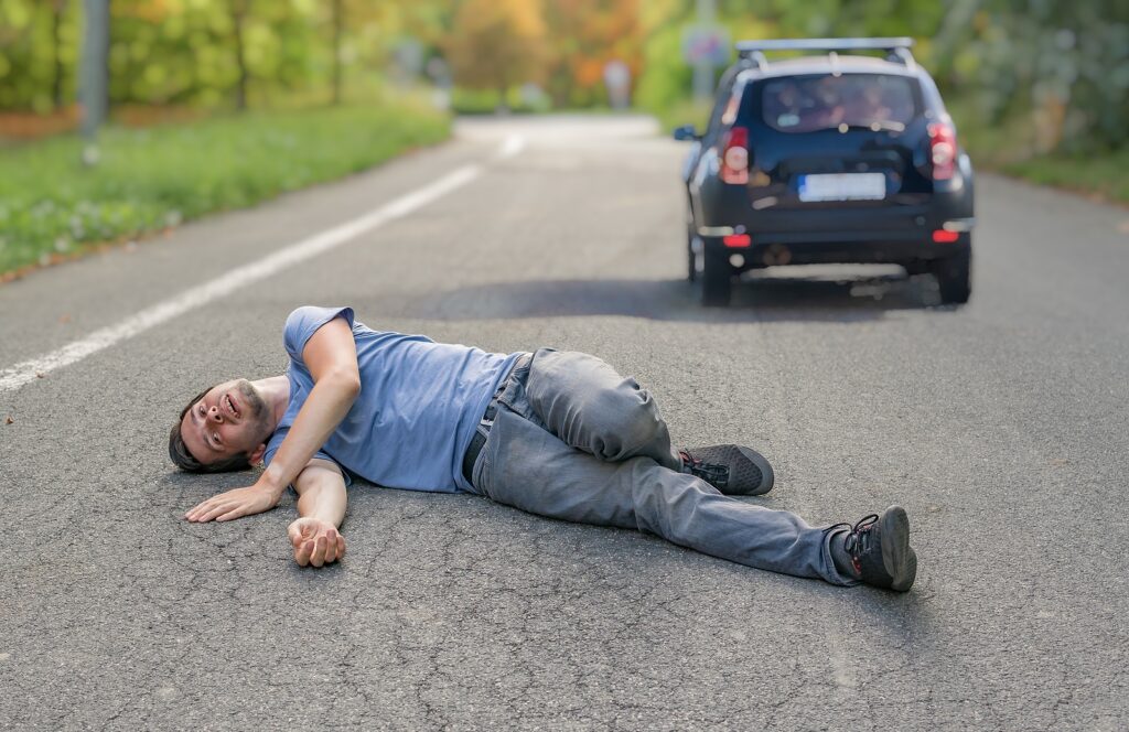 Injured man on road in front of a car