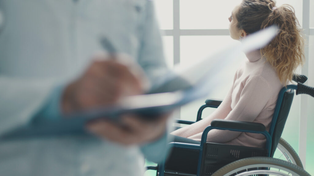 Doctor writing medical records and patient in a wheelchair